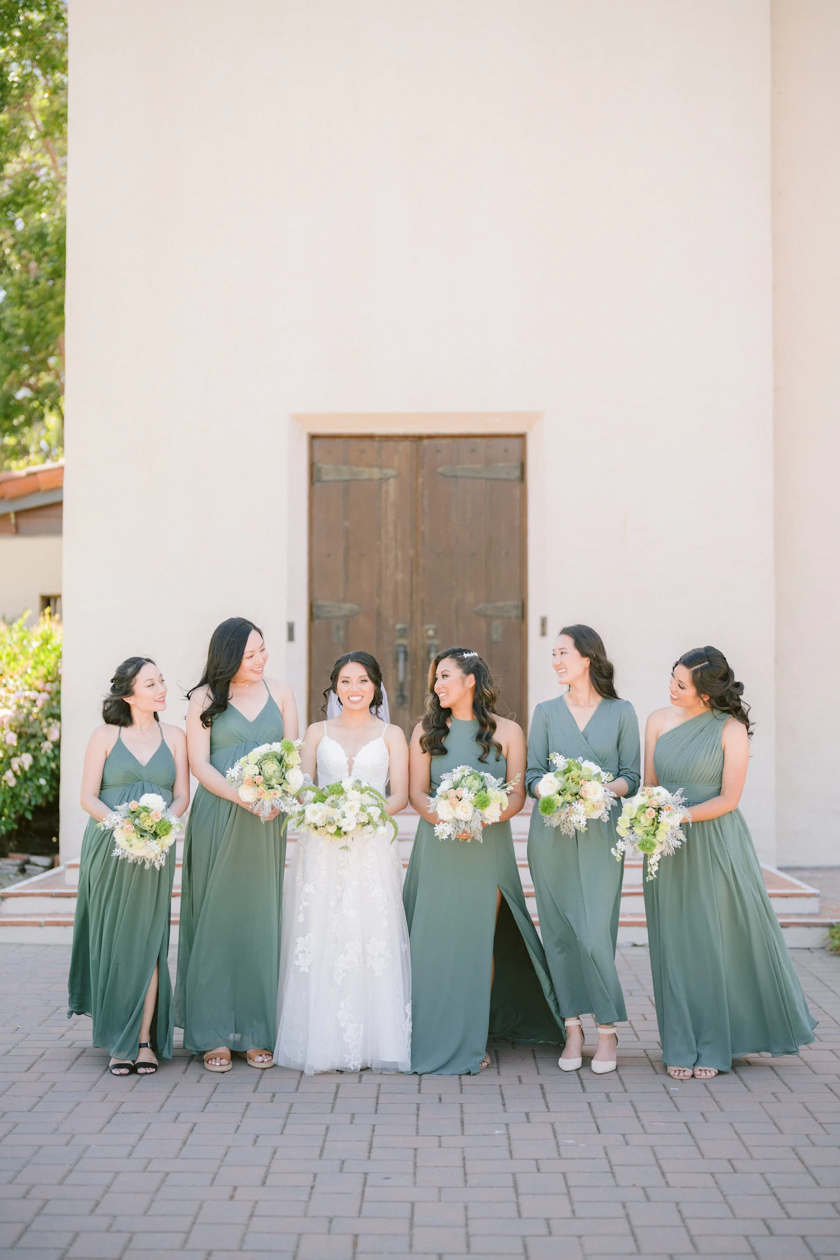 Bride and bridesmaids holding soft green and white bouquets