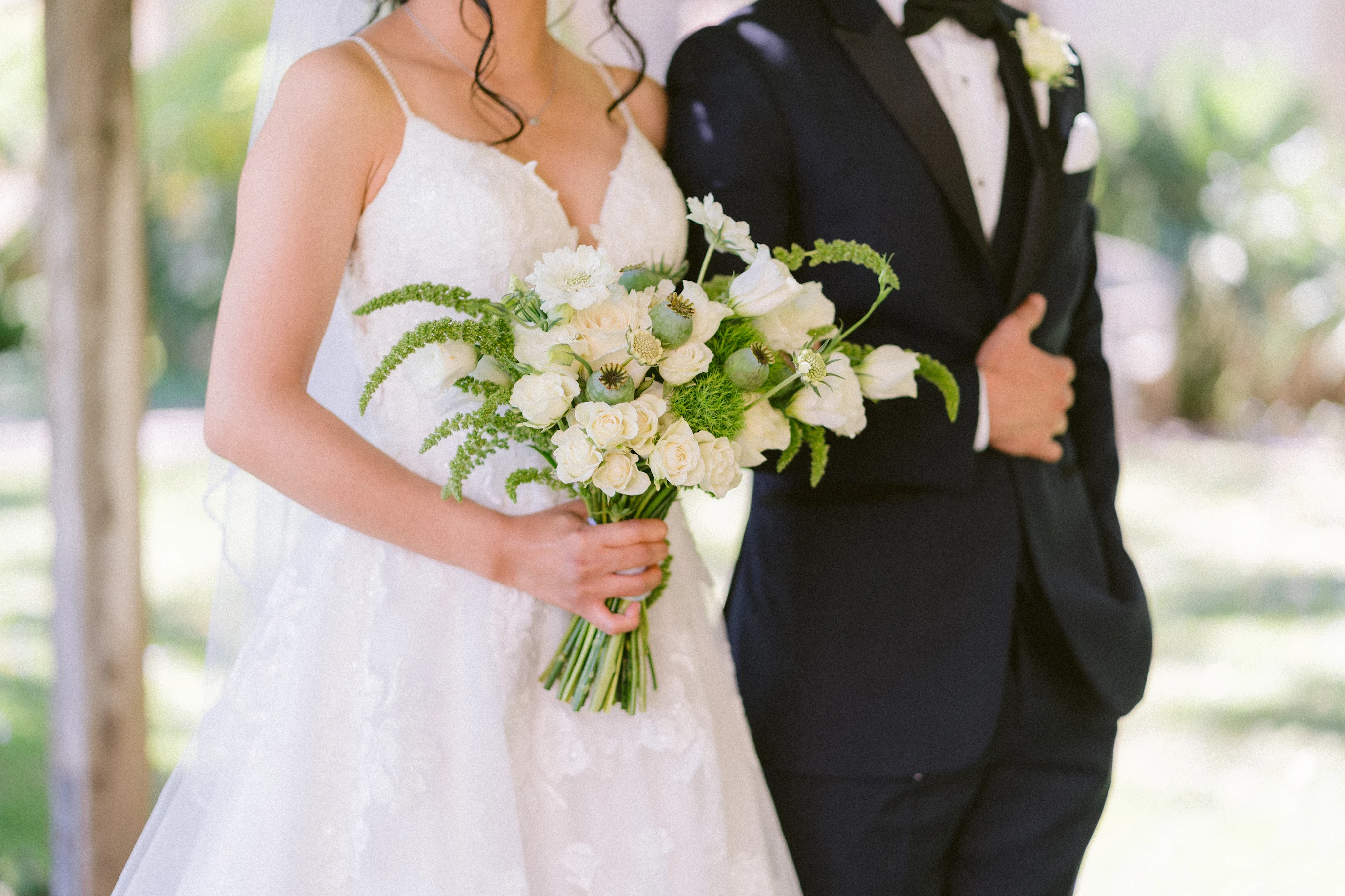 Bride and groom holding a white and green wedding bouquet